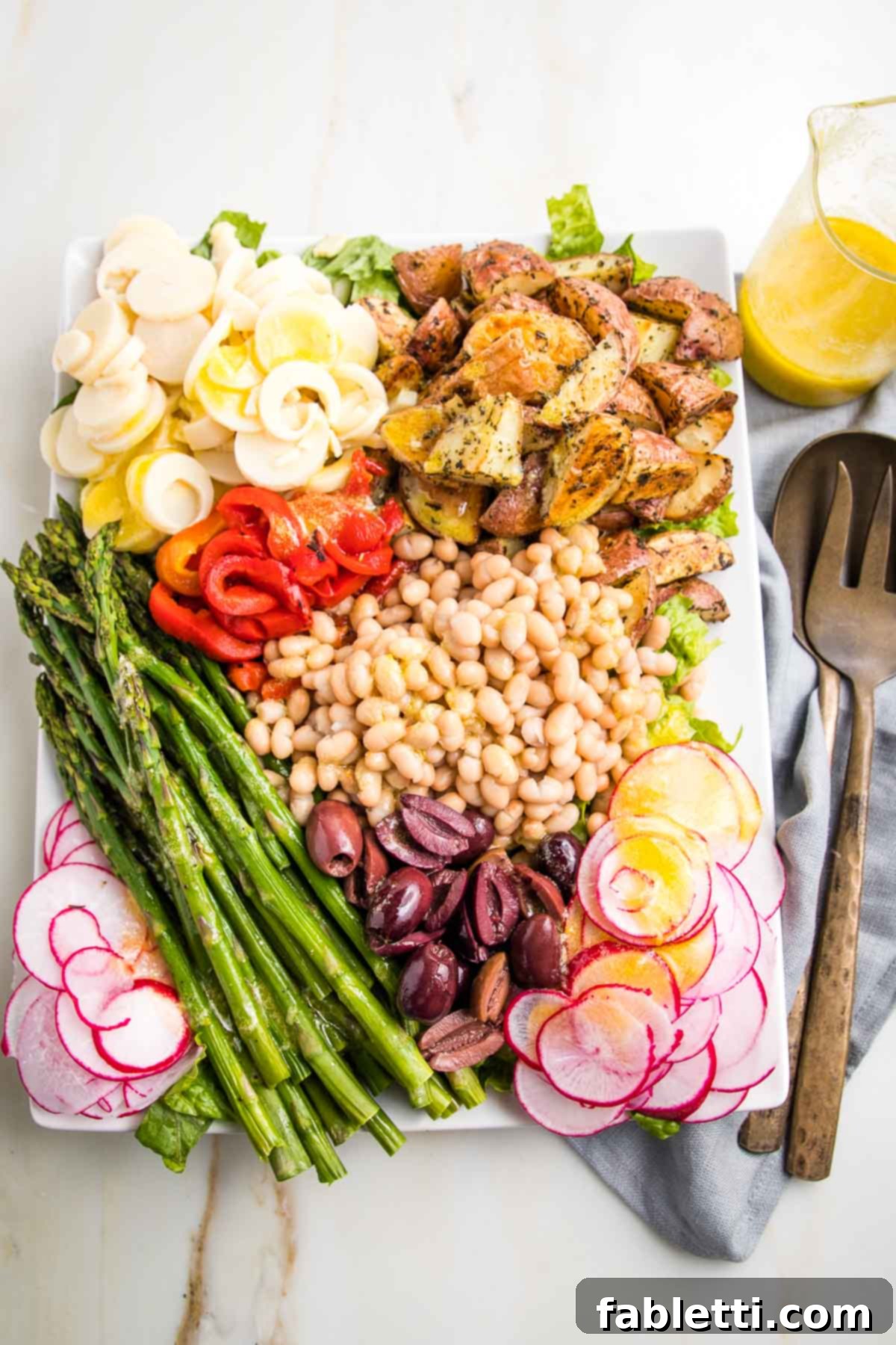 Vibrant Vegan Nicoise 2 Colorful vegan nicoise salad with lemon vinaigrette. Colorful sections of roasted potatoes, roasted red peppers, asparagus, radish, olives and white beans.