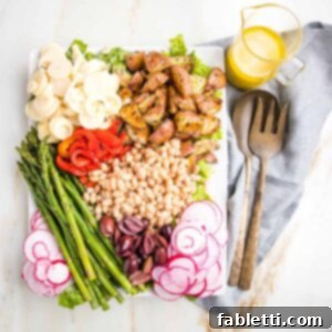 Vibrant Vegan Nicoise 14 Plattered nicoise salad with sections of roasted potatoes, red peppers, small white beans, asparagus, olives, radish and hearts of palm with a side of lemon vinaigrette.