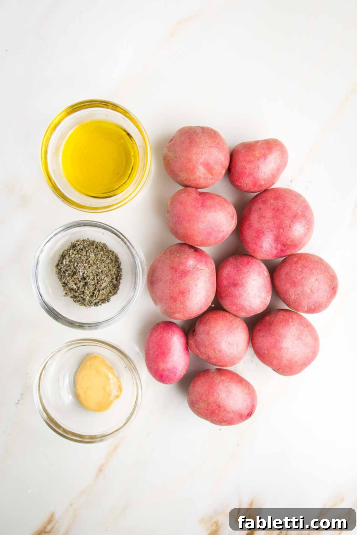 Vibrant Vegan Nicoise 5 Small red potatoes, with three tiny glass bowls with olive oil, herbs de Provence and dijon mustard.
