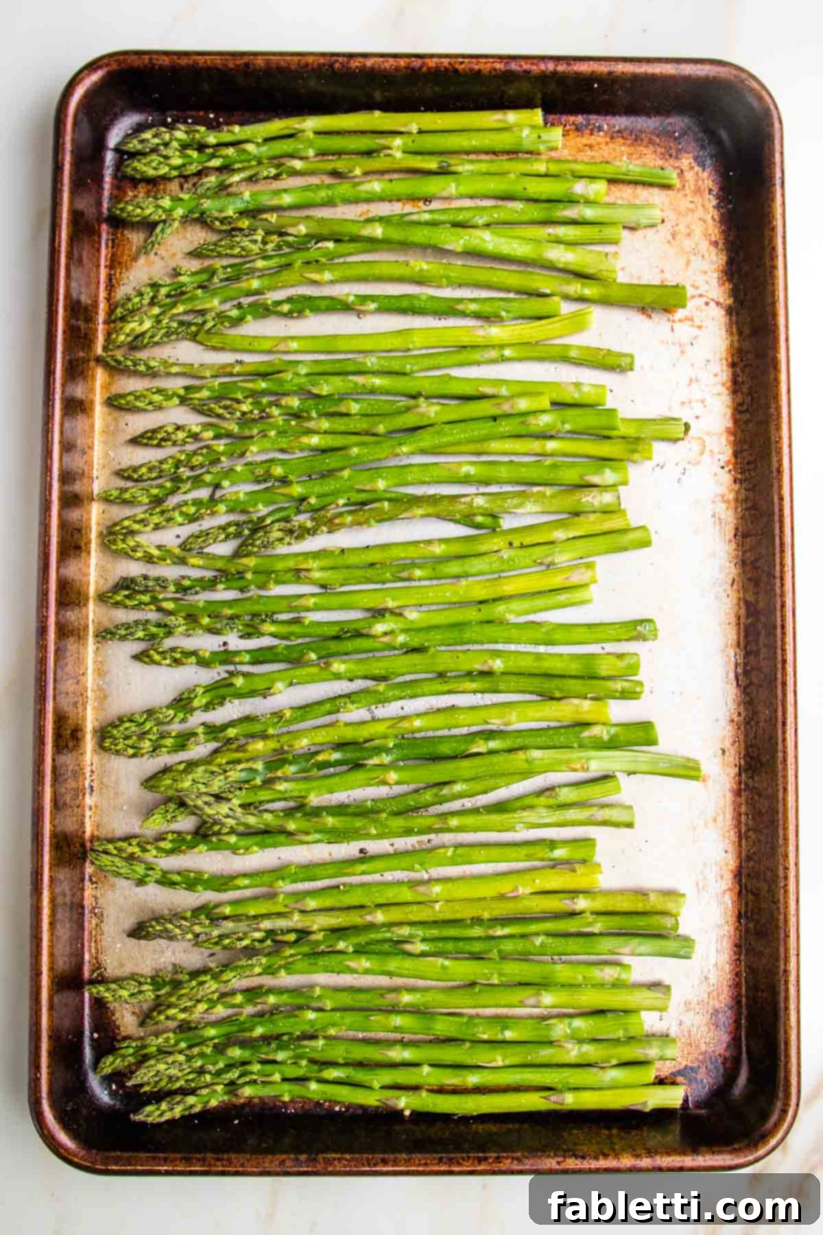 Vibrant Vegan Nicoise 8 Fresh asparagus spears on a rimmed baking sheet already roasted in the oven.