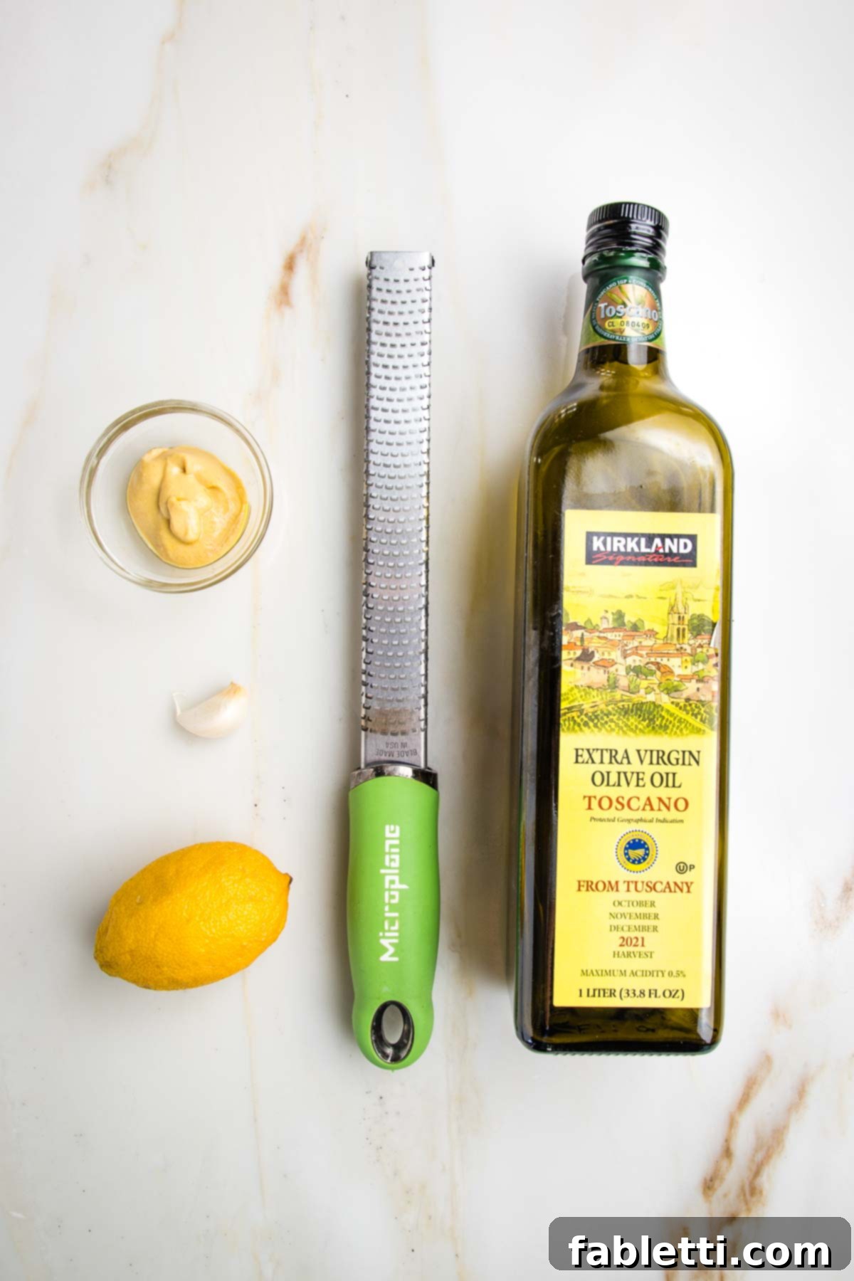Vibrant Vegan Nicoise 9 Ingredients for nicoise salad dressing: olive oil, dijon mustard, lemon and garlic shown with a microplane zester.
