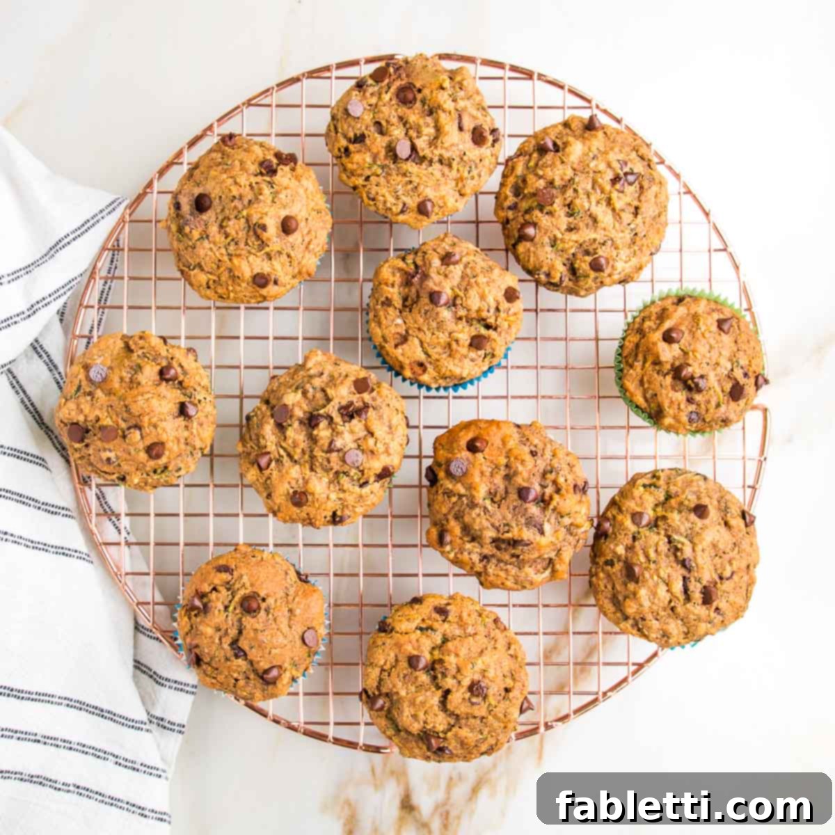 Garden Fresh Vegan Zucchini Muffins 15 Zucchini muffins with chocolate chips cooling on a wire rack.