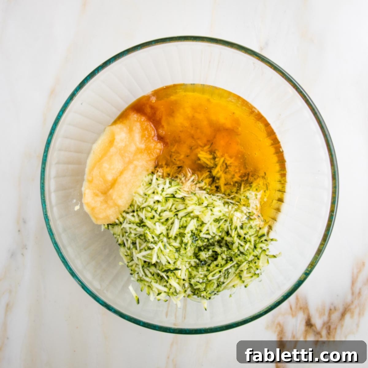 Garden Fresh Vegan Zucchini Muffins 5 Wet ingredients for zucchini muffins. In a large glass bowl: applesauce, shredded zucchini, honey, vanilla and mashed banana.