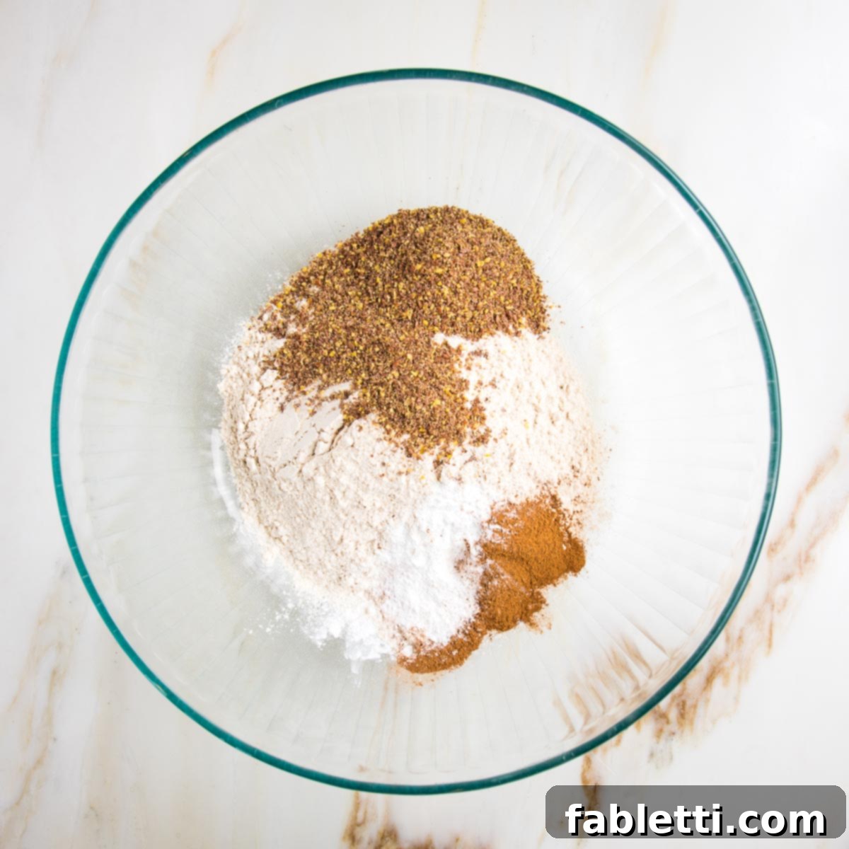 Garden Fresh Vegan Zucchini Muffins 7 Dry muffin ingredients in a glass bowl: flour, ground flax, cinnamon, baking soda and salt.