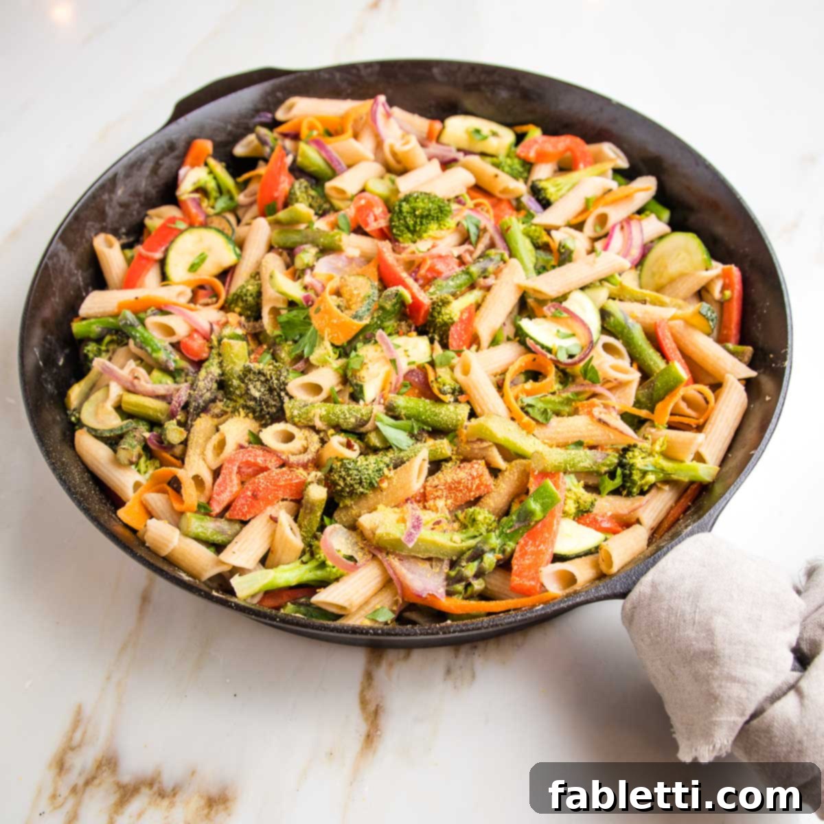 Vibrant Vegan Primavera Pasta 18 Cast iron skillet filled with colorful pasta and fresh veggies.