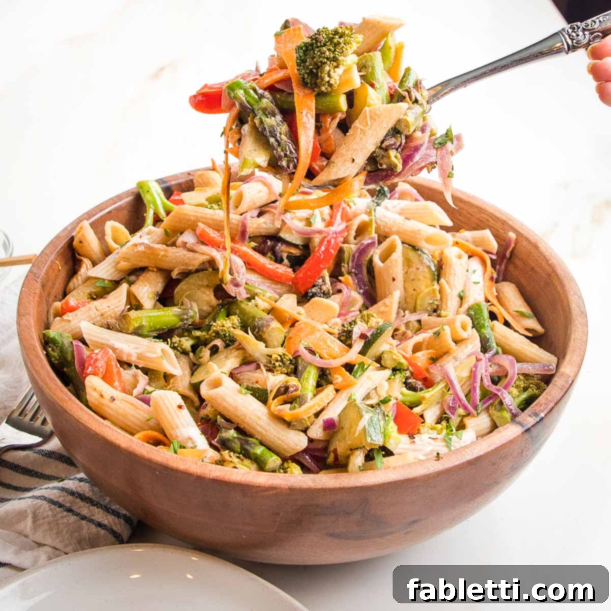 Vibrant Vegan Primavera Pasta 3 A close-up of a vibrant bowl of vegan pasta primavera, showcasing the colorful fresh vegetables and creamy sauce, garnished with fresh herbs and lemon wedges.