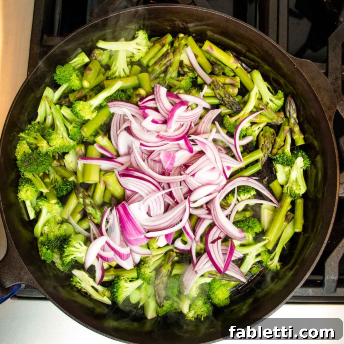 Vibrant Vegan Primavera Pasta 8 Broccoli stalks and asparagus spears sizzling in a skillet with a light swirl of olive oil.