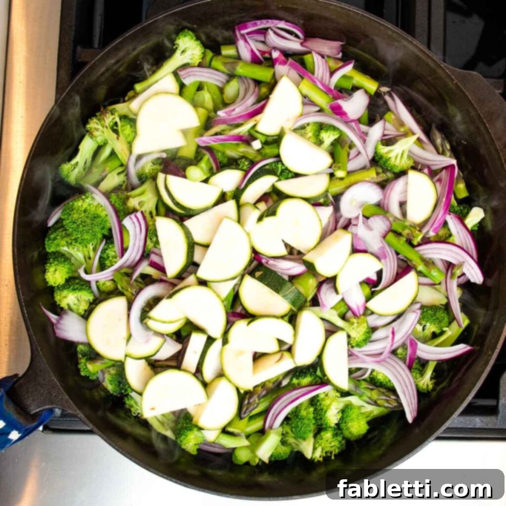 Vibrant Vegan Primavera Pasta 9 Red onions joining broccoli and asparagus in the skillet, starting to soften and become translucent.