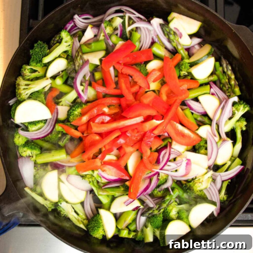 Vibrant Vegan Primavera Pasta 10 A mix of broccoli, asparagus, and red onions in a skillet, gently sautéing.