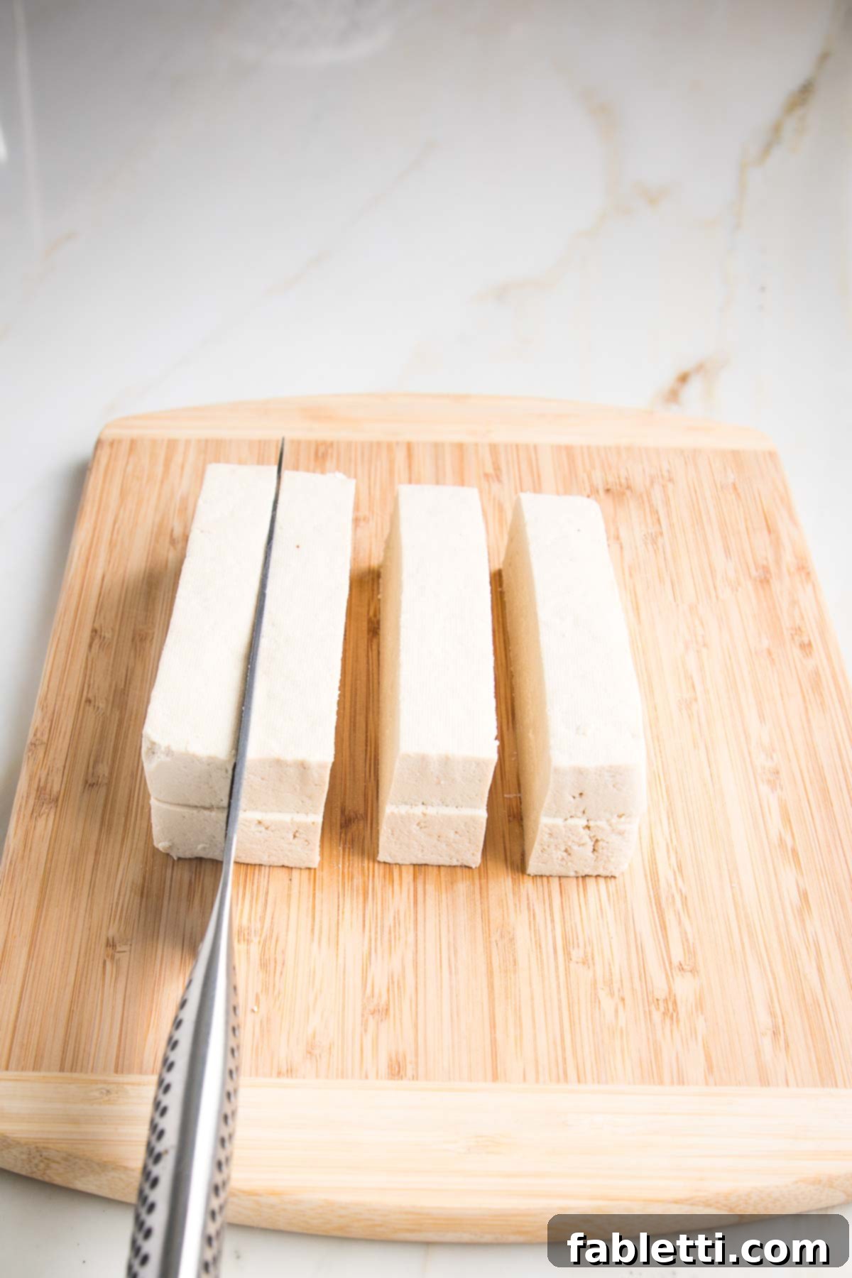 Grilled Tofu Satay with Creamy Peanut Sauce 11 Drained tofu on a wooden board, slicing through to produce 8 equal long satay slices.