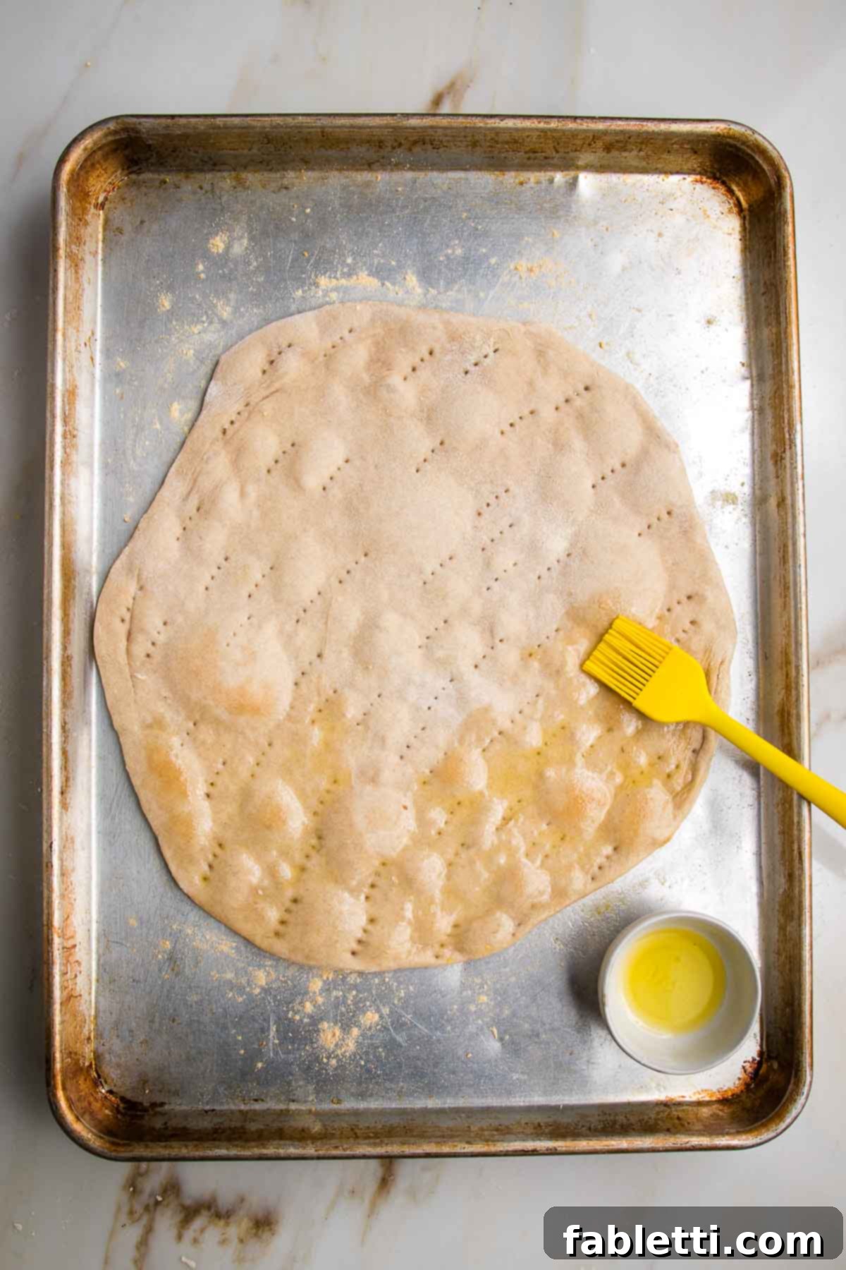 Effortless Yeast-Free Flatbread Pizza 14 Flatbread pizza dough, partially cooked and being brushed with olive oil, showing a golden hue and readiness for its final bake.
