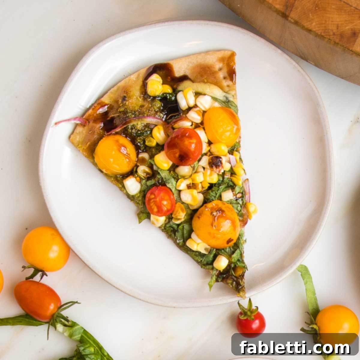 Effortless Yeast-Free Flatbread Pizza 20 A vibrant slice of flatbread topped with colorful tomatoes, sweet corn, fresh onions, and fragrant basil, presented on a small white-rimmed plate, invitingly delicious.