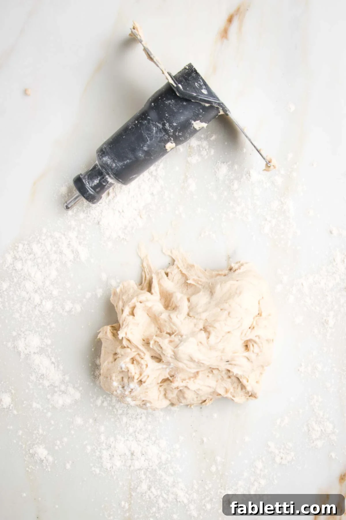 Effortless Yeast-Free Flatbread Pizza 7 A smooth ball of no yeast flatbread dough, alongside a food processor blade, resting on a lightly floured marble counter, ready for kneading.