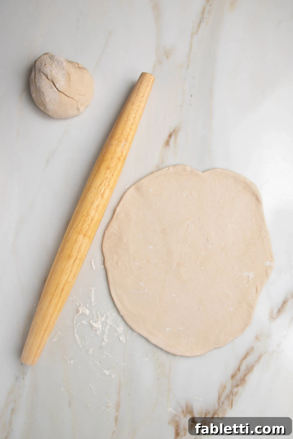 Effortless Yeast-Free Flatbread Pizza 10 A ball of dough, a wooden rolling pin, and a circular flatbread dough perfectly rolled out, demonstrating the ideal shape and thinness.
