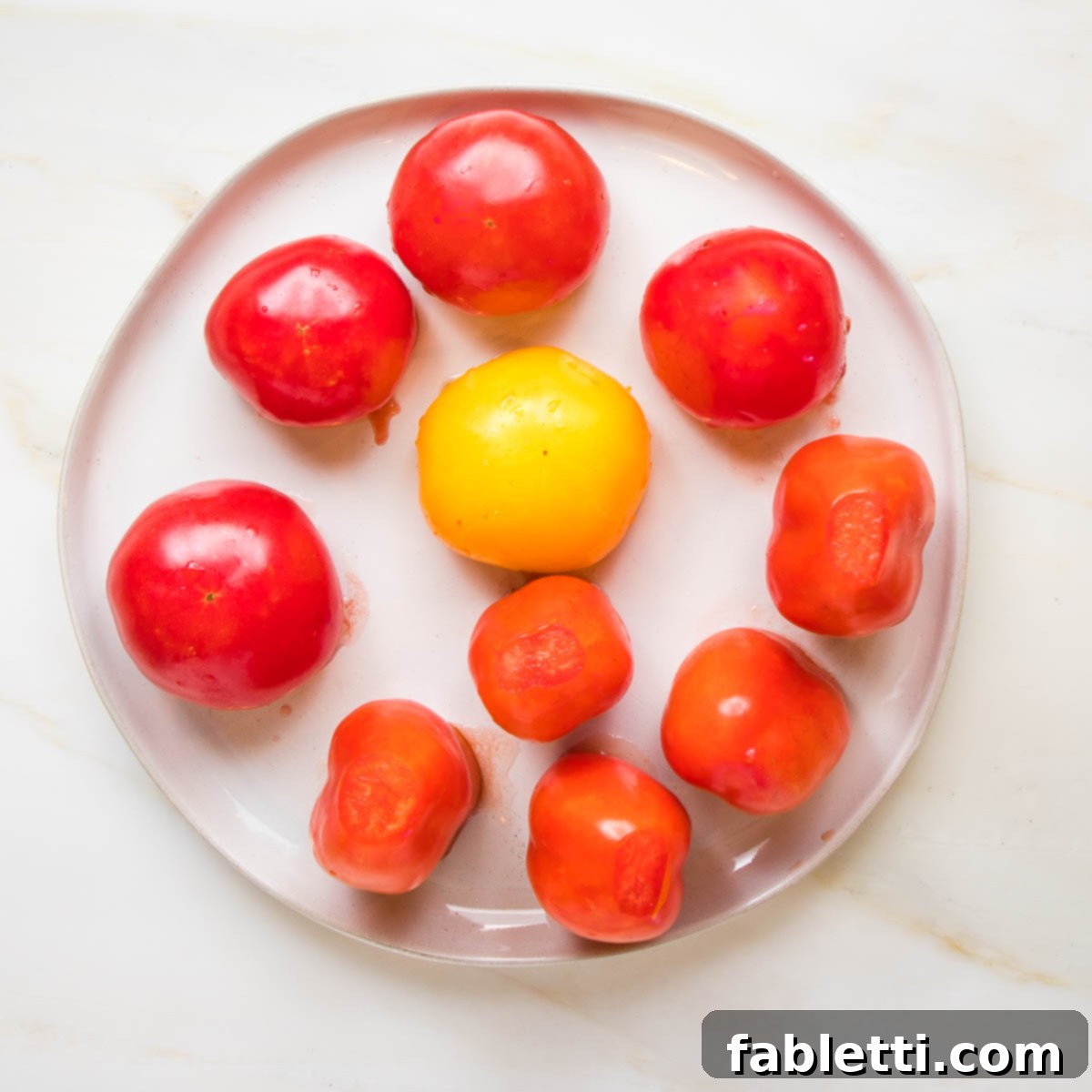 Plant-Powered Stuffed Tomatoes 7 Scooped-out tomatoes with their tops cut off, placed upside down on a plate to drain excess liquid.