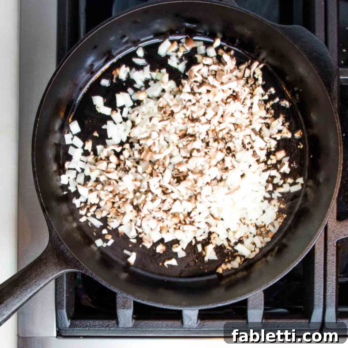 Plant-Powered Stuffed Tomatoes 9 Cast iron skillet containing diced mushrooms and onions, gently sautéing.