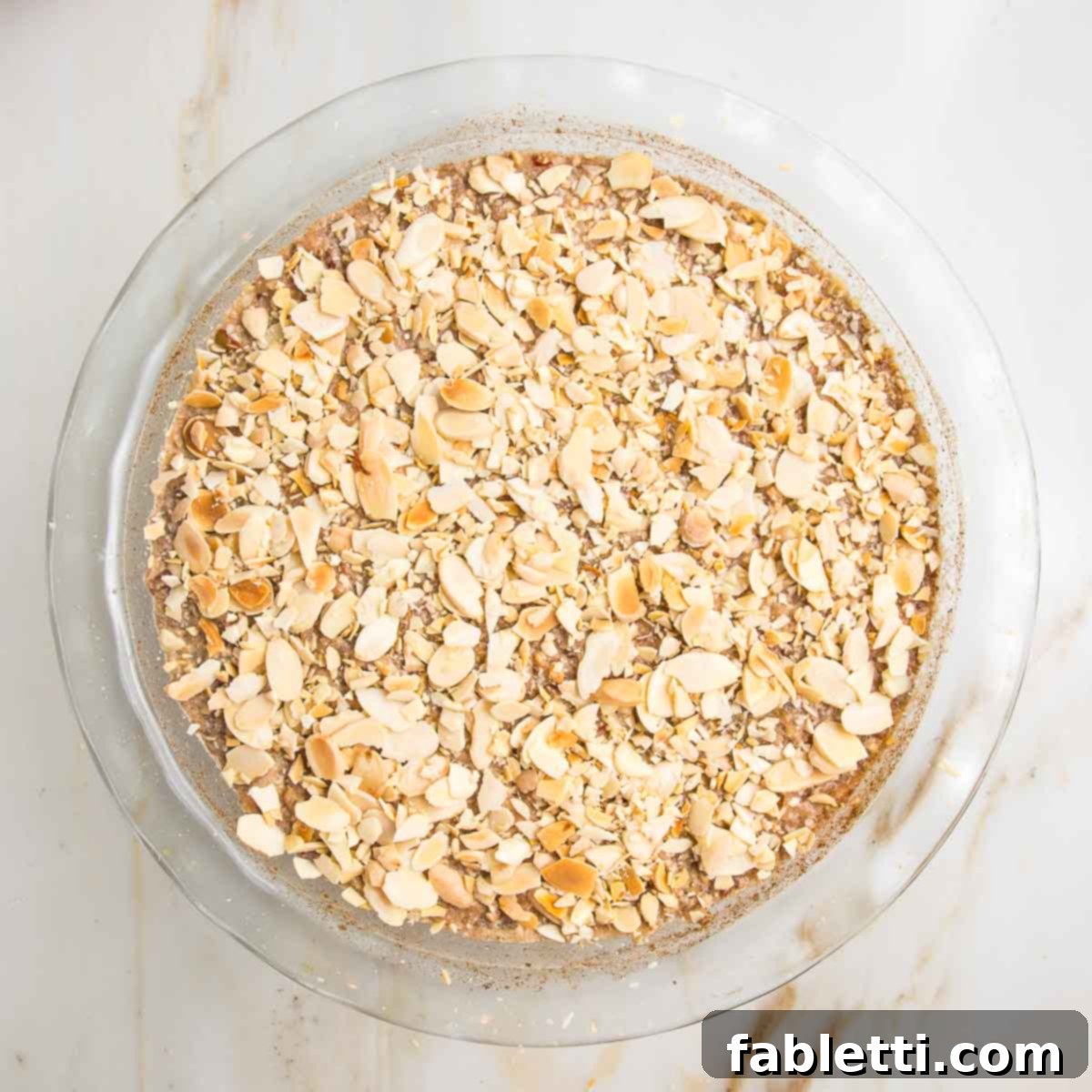 Hearty Baked Steel-Cut Oats 12 Steel cut oat mixture, topped with sliced almonds in a pie plate, ready to bake.