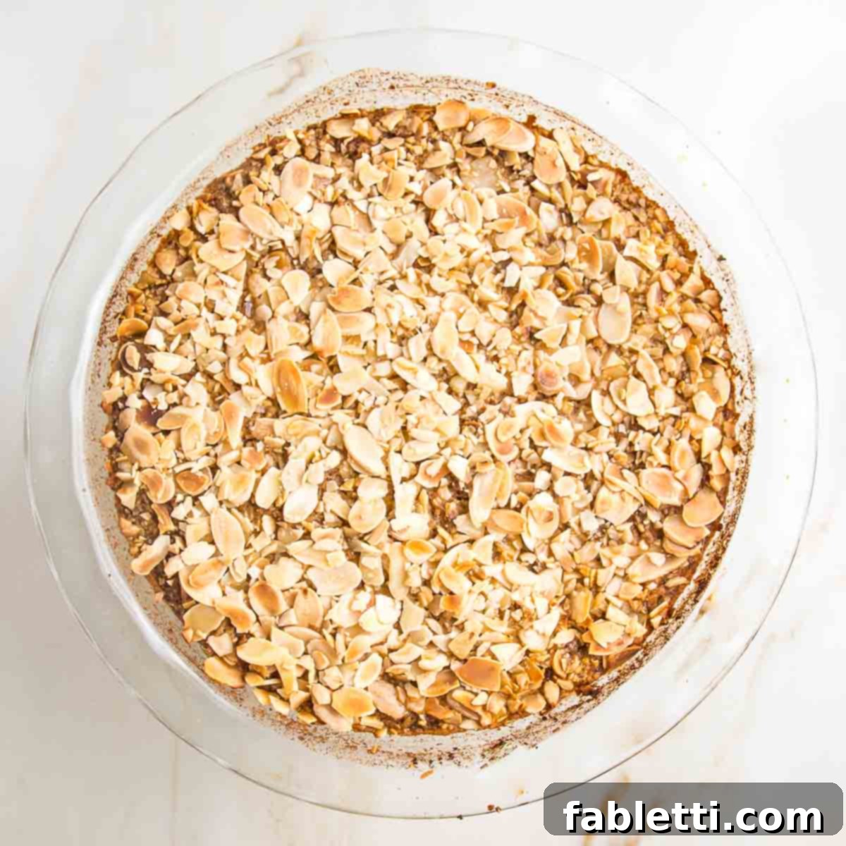 Hearty Baked Steel-Cut Oats 13 Baked steel cut oats topped with sliced almonds in a pie plate.