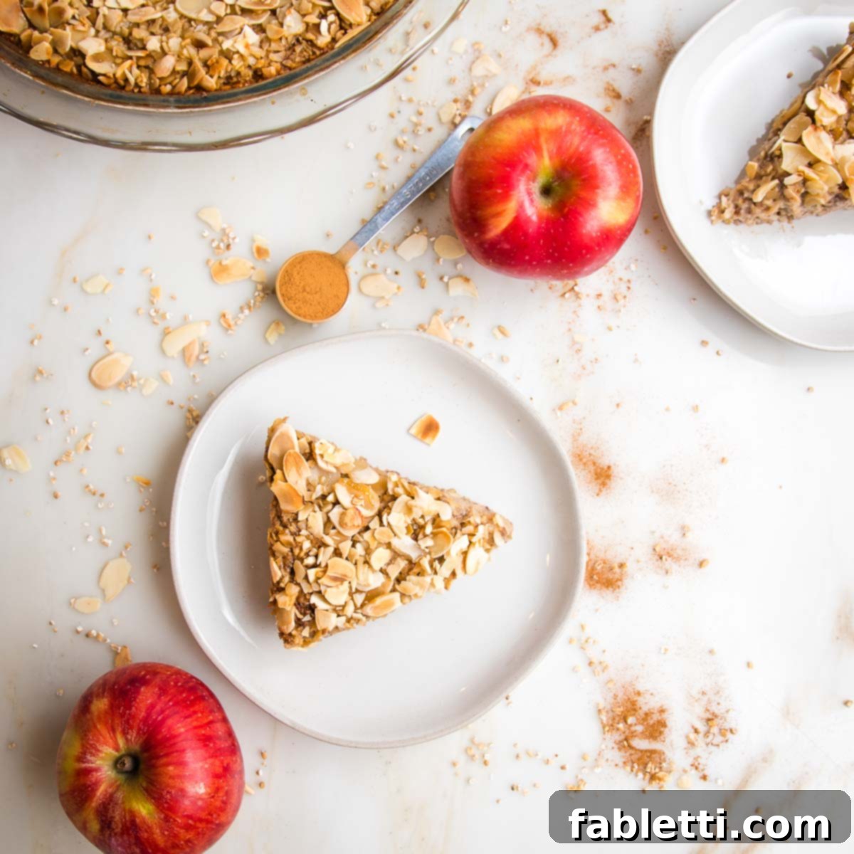 Hearty Baked Steel-Cut Oats 14 Slices of baked steel cut oats on white plates, surrounded by whole apples, and a teaspoon of cinnamon.