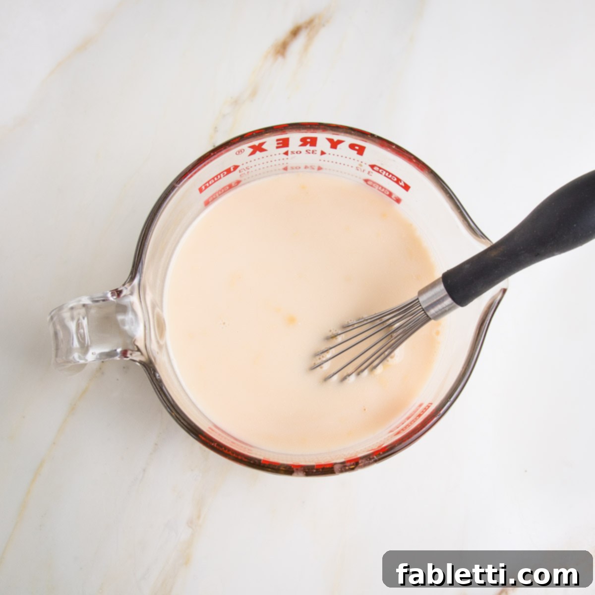 Hearty Baked Steel-Cut Oats 7 Large pyrex measuring cup with whisk and plant milk mixture.