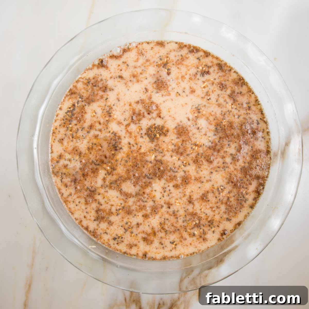 Hearty Baked Steel-Cut Oats 8 Glass pie plate with steel cut oats, almond milk and spices mixed together.