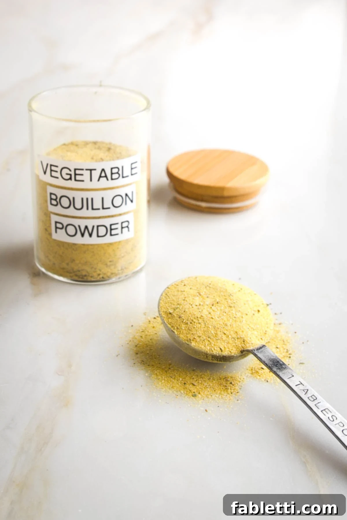 Garden Gold Broth Mix 4 Small jar with yellow powder labeled "vegetable bouillon powder" and a Tablespoon of the powder on the counter.