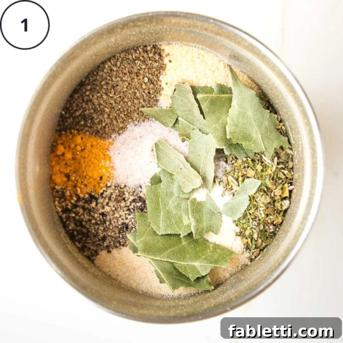 Garden Gold Broth Mix 5 Spice grinder filled with colorful spices, crumbled bay leaves, salt and pepper.