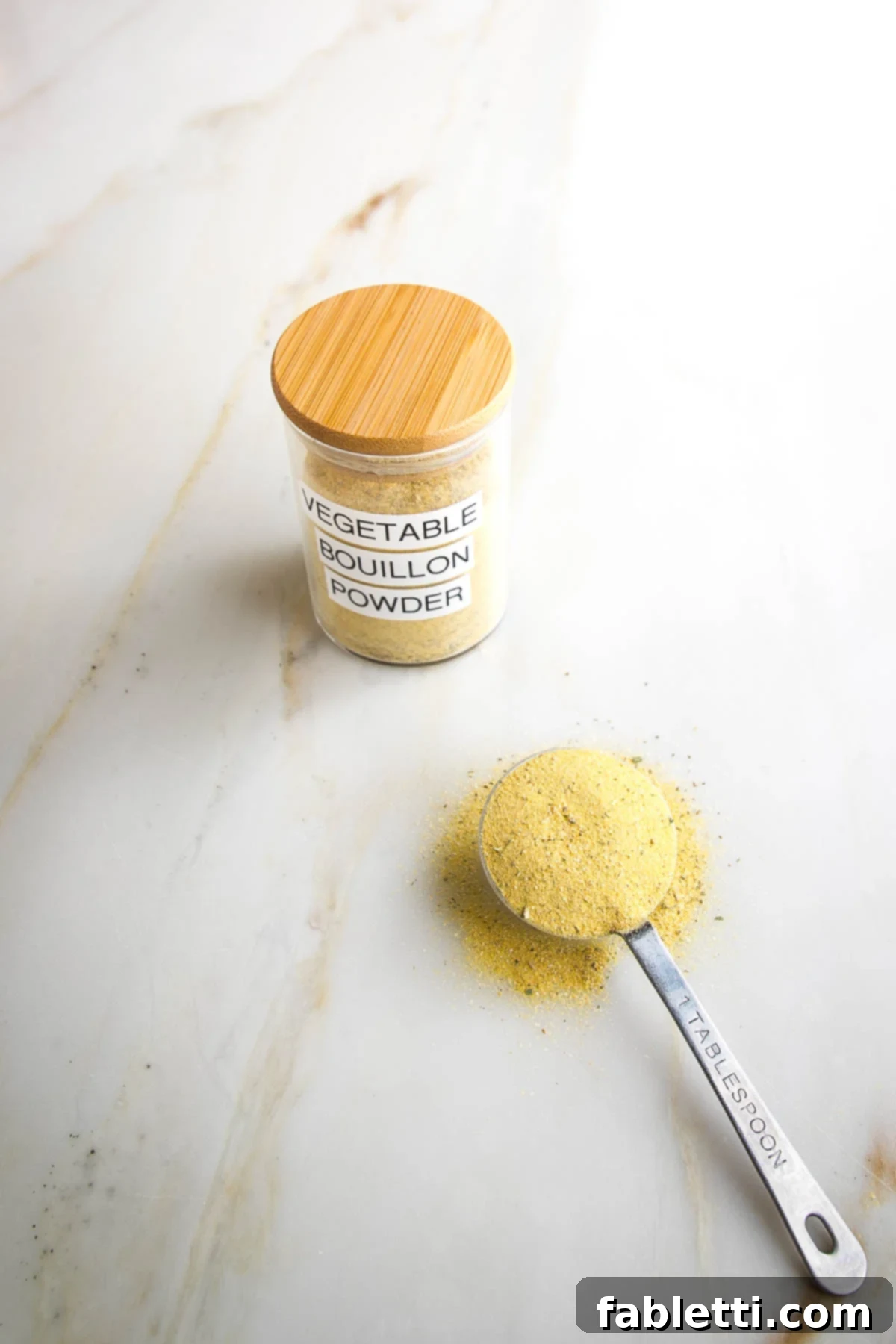 Garden Gold Broth Mix 7 Vegetable Bouillon Powder labeled on jar with yellowish powder. A Tablespoon with same yellow spice mixture in the foreground.