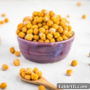 Golden Crispy Chickpea Bites 10 Crunchy chickpeas piled into a purple bowl with a spoon of them in the foreground.