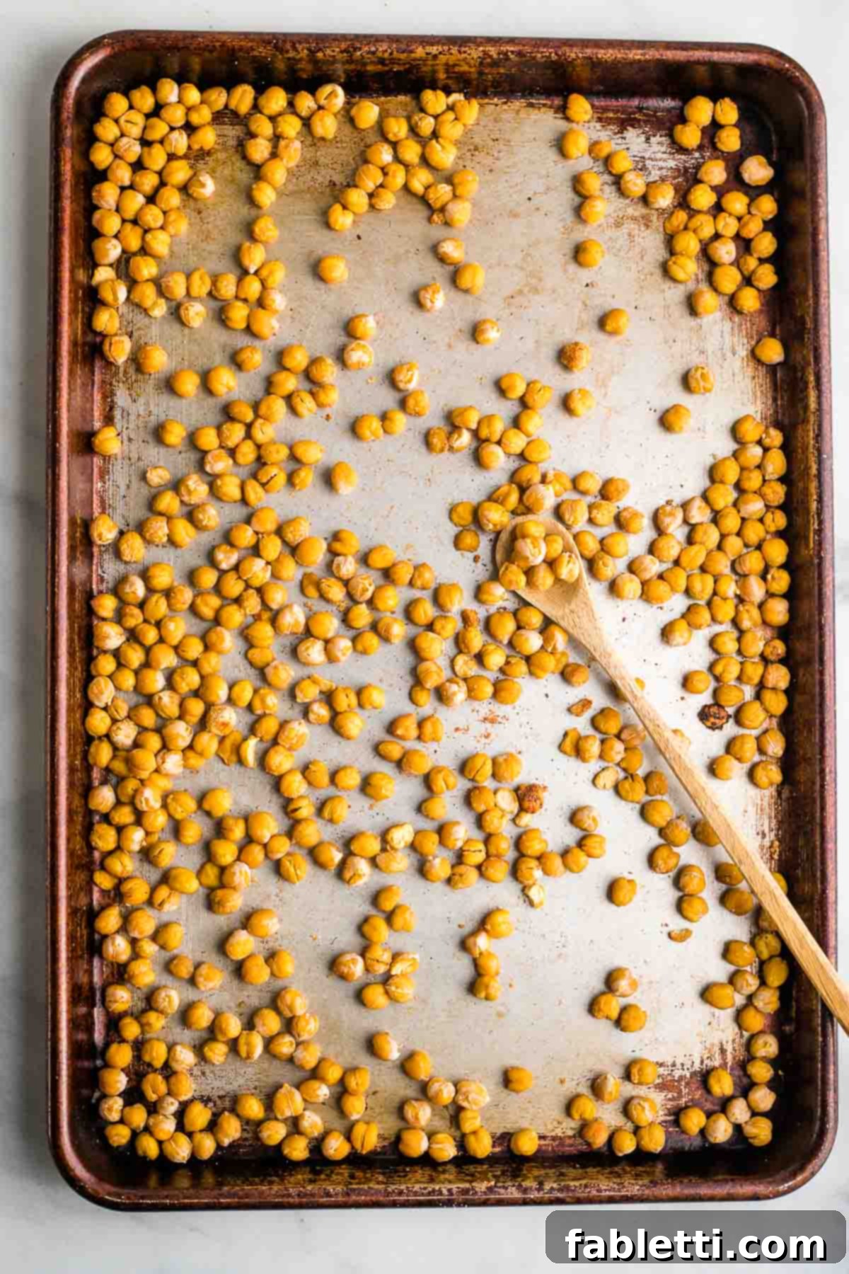 Golden Crispy Chickpea Bites 6 Crunchy roasted chickpeas on a baking sheet with spoon.