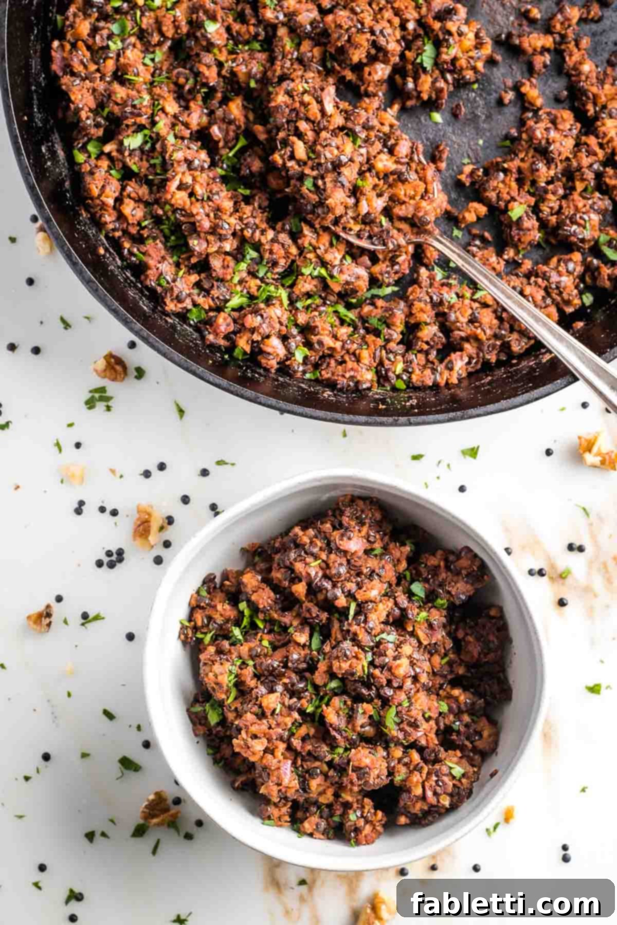 Umami-Packed Vegan Mushroom Lentil Crumble 2 A cast iron skillet holds a generous portion of homemade vegan ground beef, with a serving spoon resting beside it. A smaller bowl of the plant-based meat is visible in the background, showcasing its rich, crumbly texture.