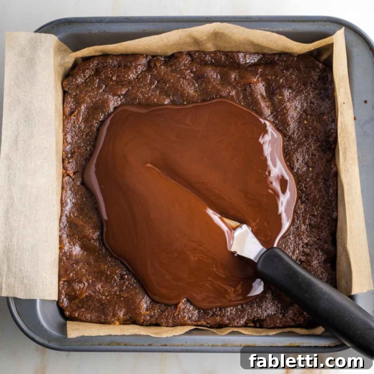 Guilt-Free Homemade Twix Bars 16 An offset spatula meticulously spreading the melted chocolate towards the corners of the pan, creating a perfectly smooth, even top layer.