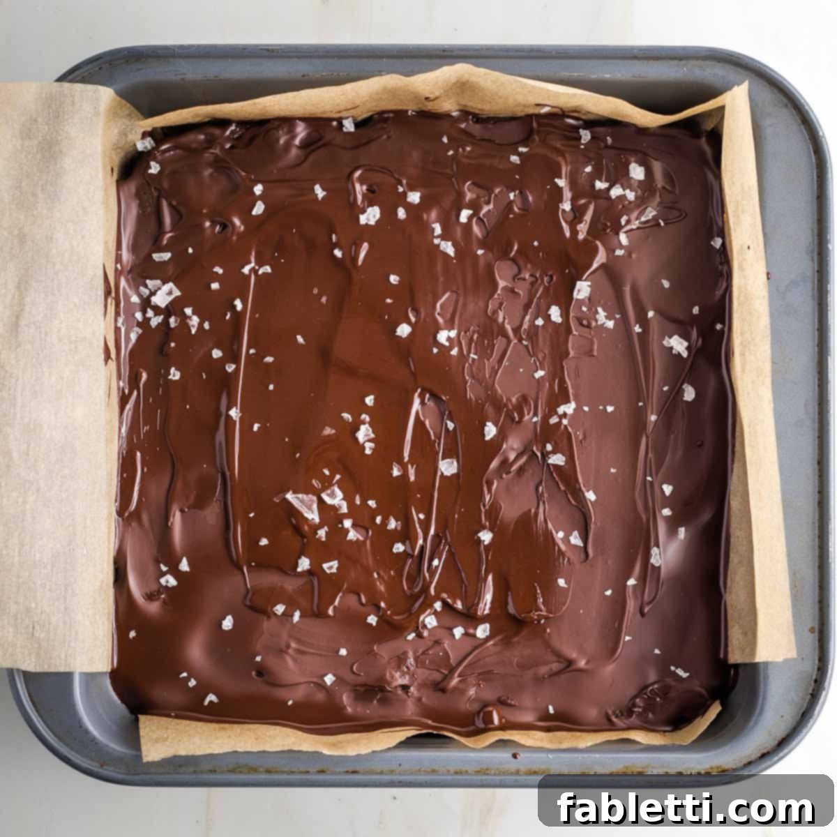 Guilt-Free Homemade Twix Bars 17 The square baking pan filled with homemade twix, the smooth chocolate layer on top lightly sprinkled with flakey sea salt.