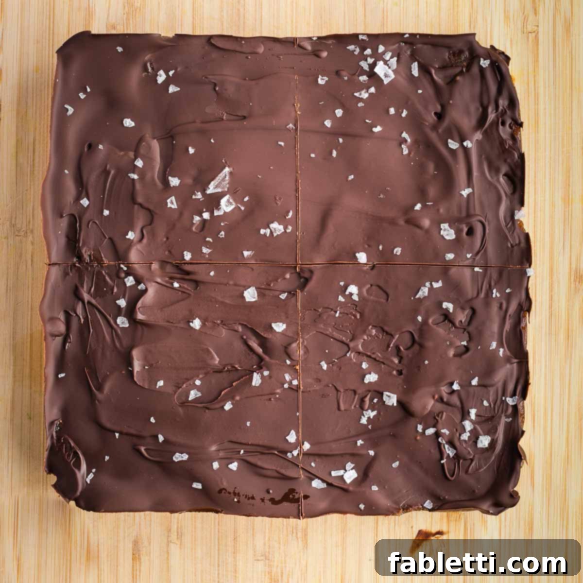 Guilt-Free Homemade Twix Bars 18 A square of chocolate topping with initial, shallow cut lines marking it into four equal quarters.