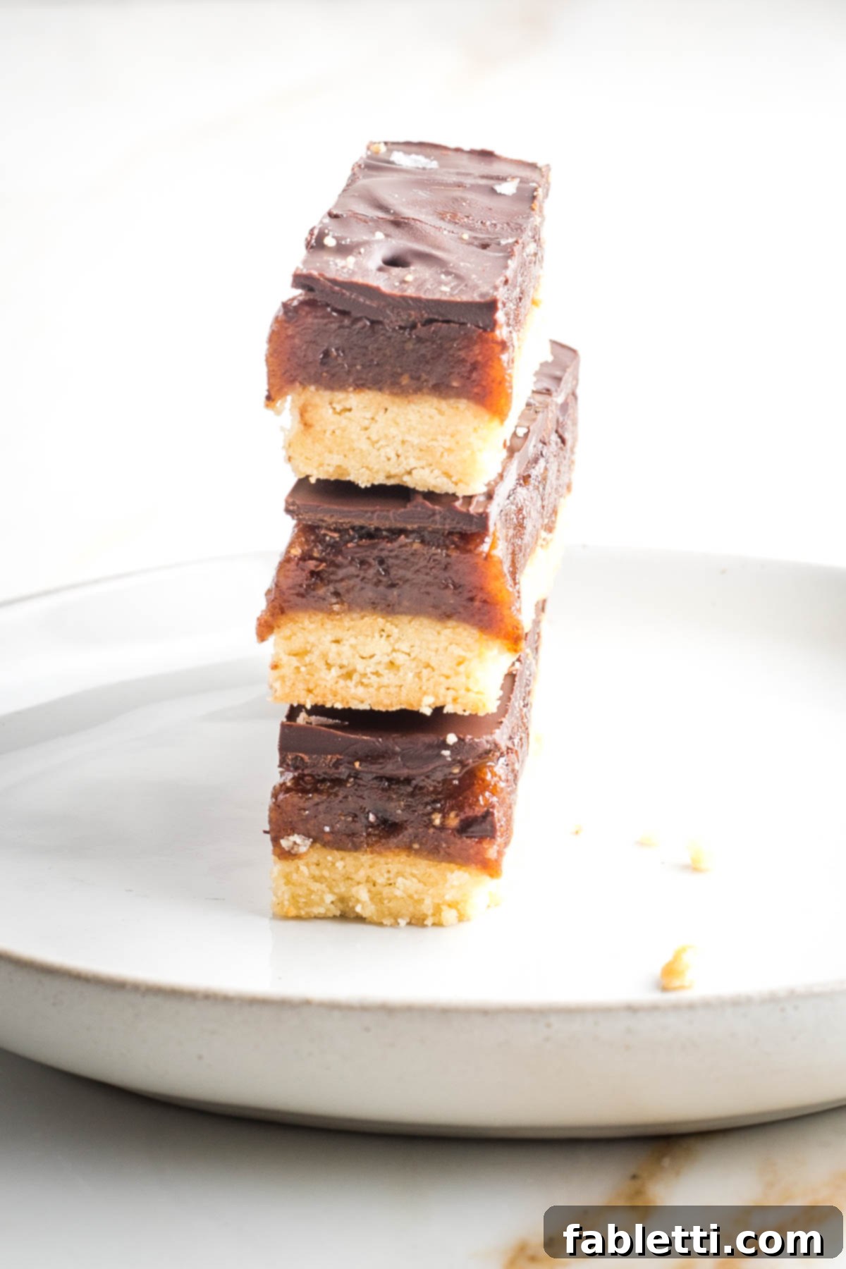 Guilt-Free Homemade Twix Bars 3 Three homemade twix bars stacked on top of each other. You can see the three distinct layers: crisp cookie, rich caramel, and smooth chocolate on the side.