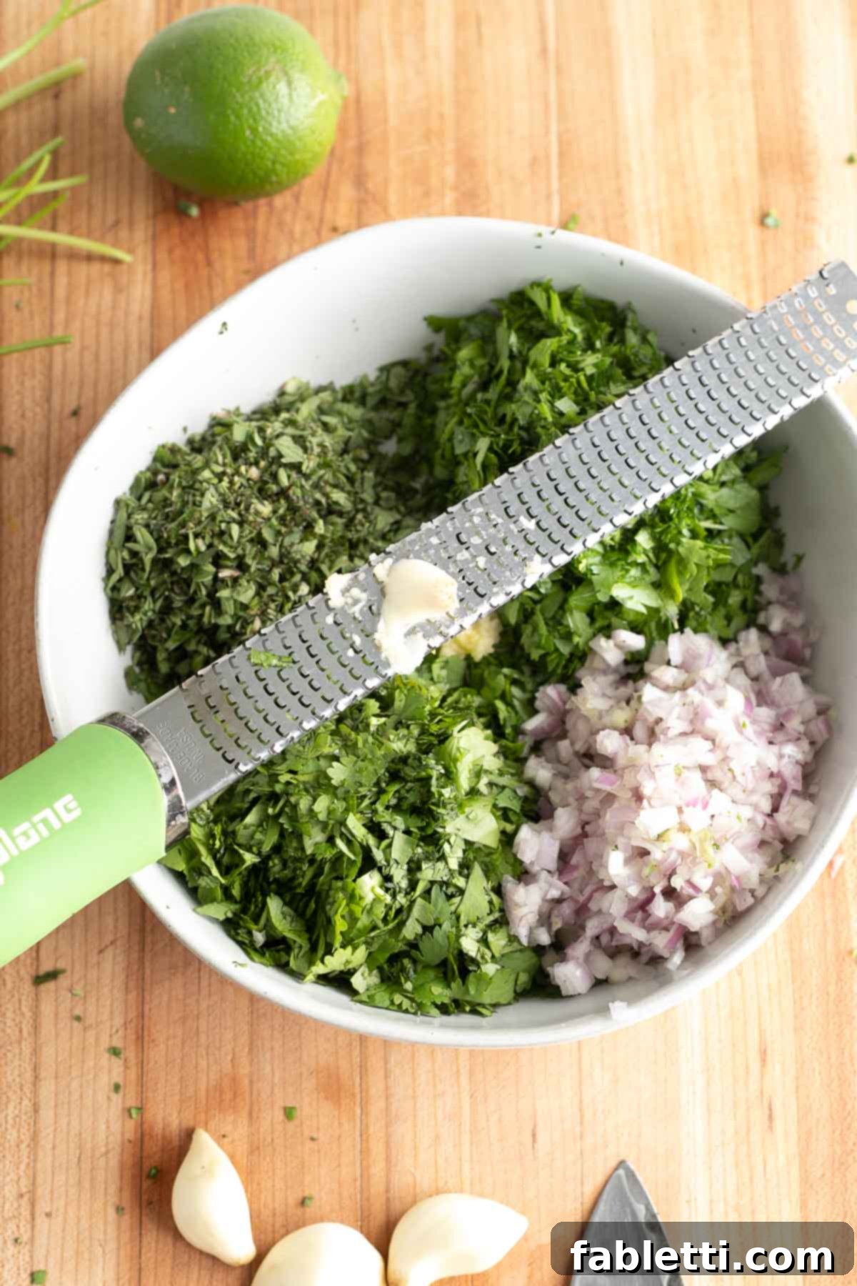 Vibrant Cilantro Chimichurri 6 Finely grating garlic over a bowl of chopped herbs and onions, releasing its pungent aroma.