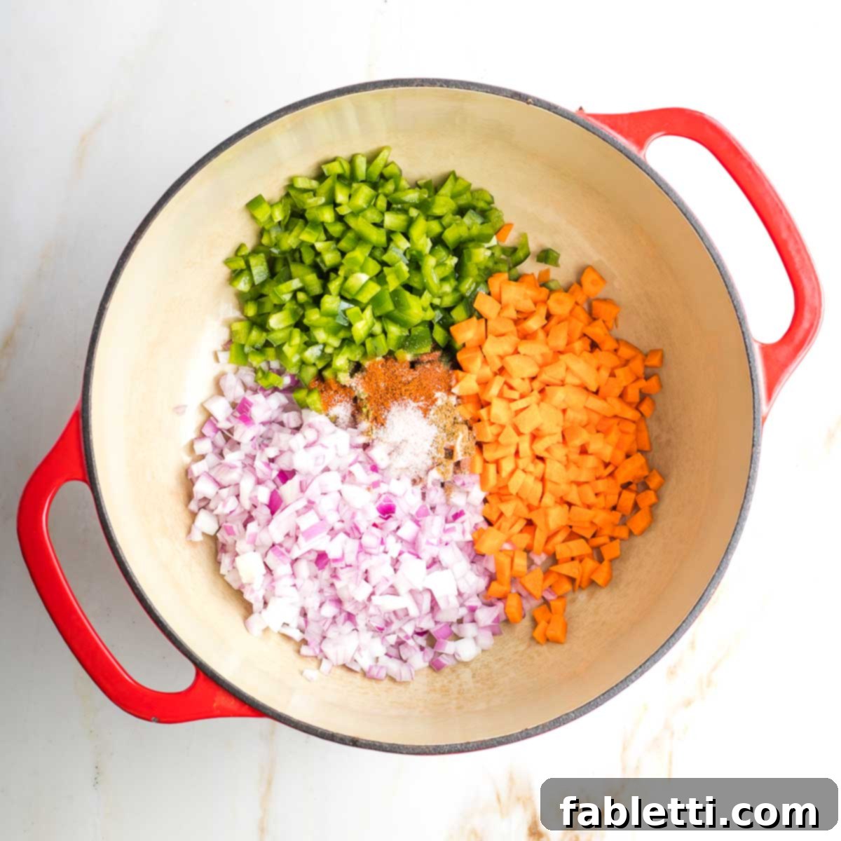 Dutch oven with sections of chopped onion, carrot and green pepper.
