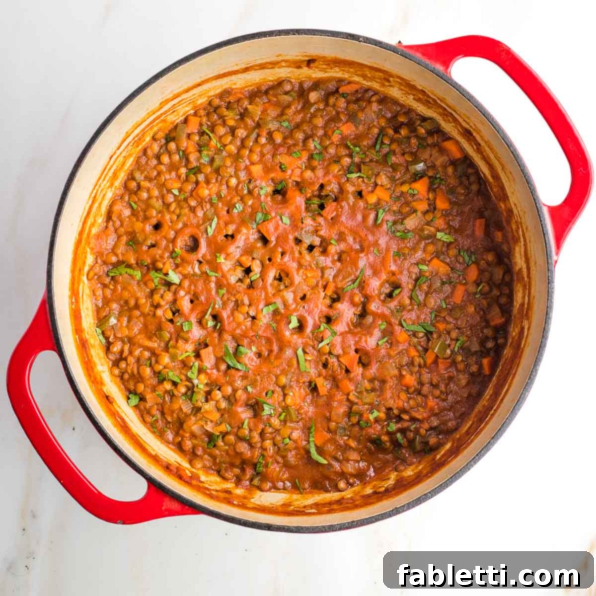 Vegan sloppy joes in a dutch oven, sprinkled with fresh herbs.