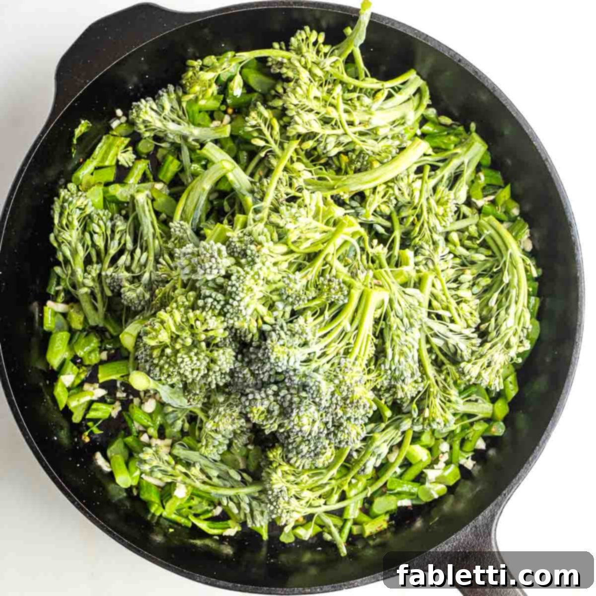 Cast iron skillet with sauteed baby broccoli stems, florets piled on top.
