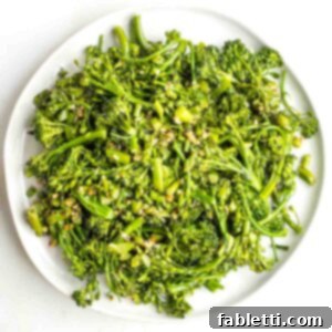 Plate filled with cooked baby broccoli with pieces of garlic.