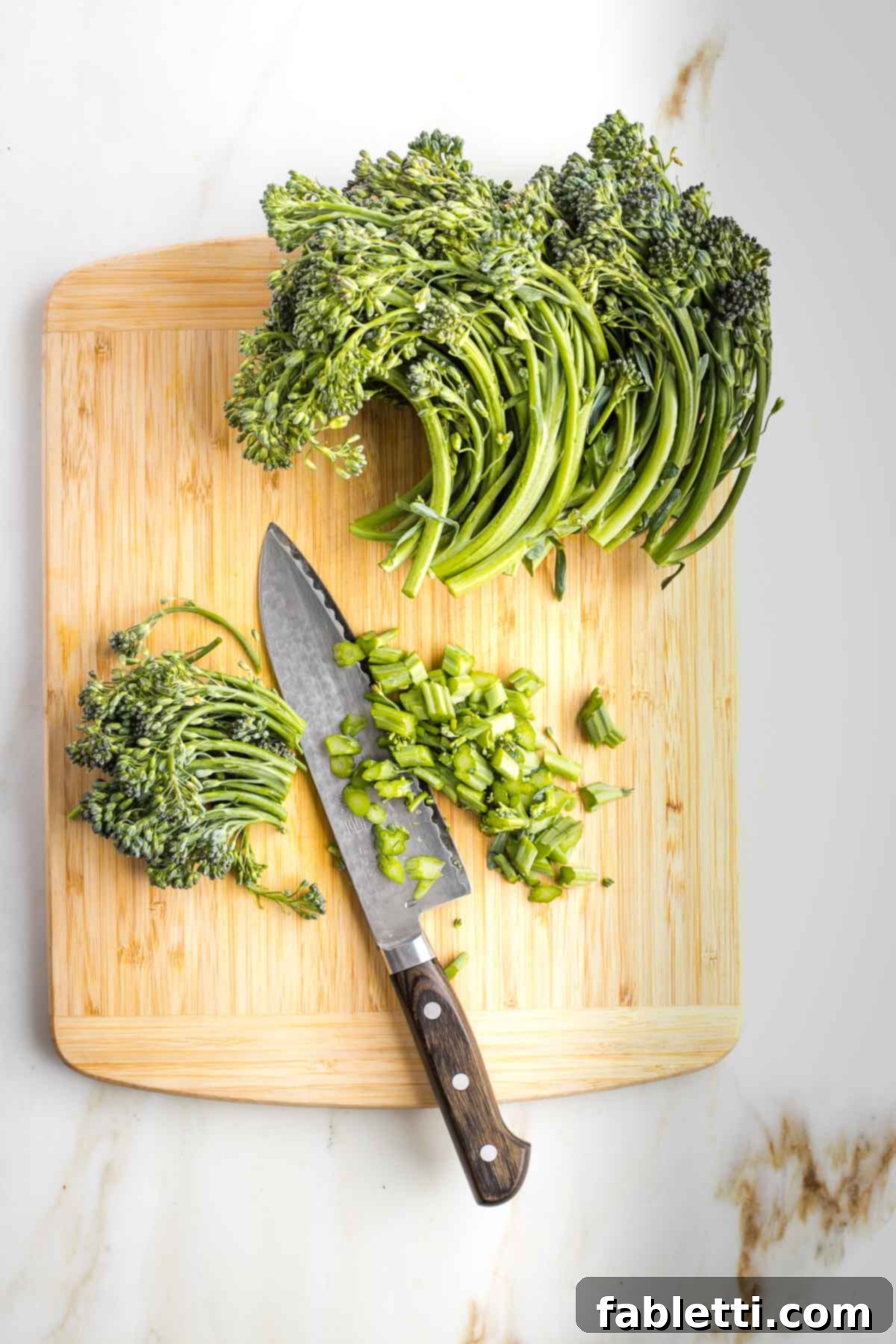 Knife showing how to cut the bottom ⅓ of broccolini stems.