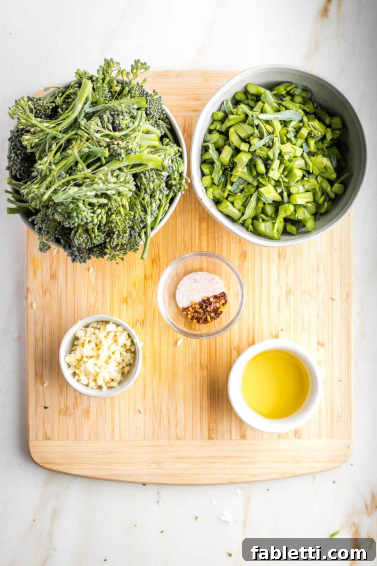 Prep bowls with trimmed broccolini, minced garlic, spices and oil.