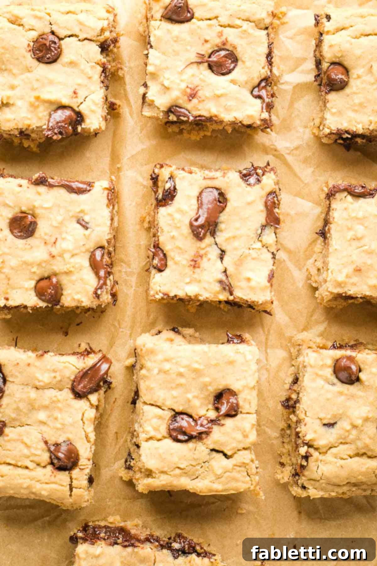 Bean-Powered Vegan Blondies 14 Squares of chocolate chip blondies on a piece of unbleached parchment paper.