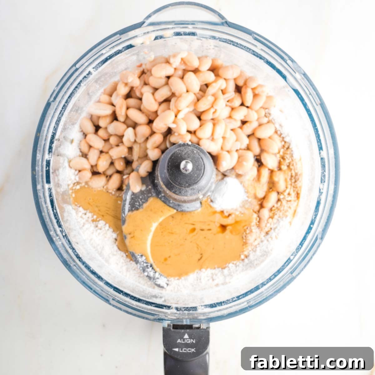 Bean-Powered Vegan Blondies 7 Food processor bowl withwhite beans, flour, tahini, baking powder and syrup.