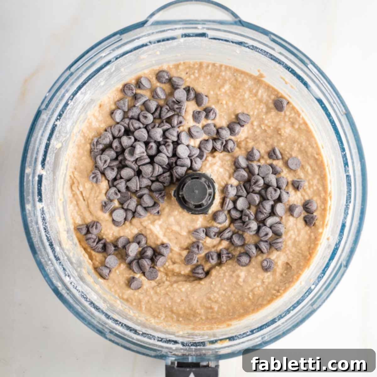 Bean-Powered Vegan Blondies 9 Blondie batter in food processor bowl with chocolate chips on top.