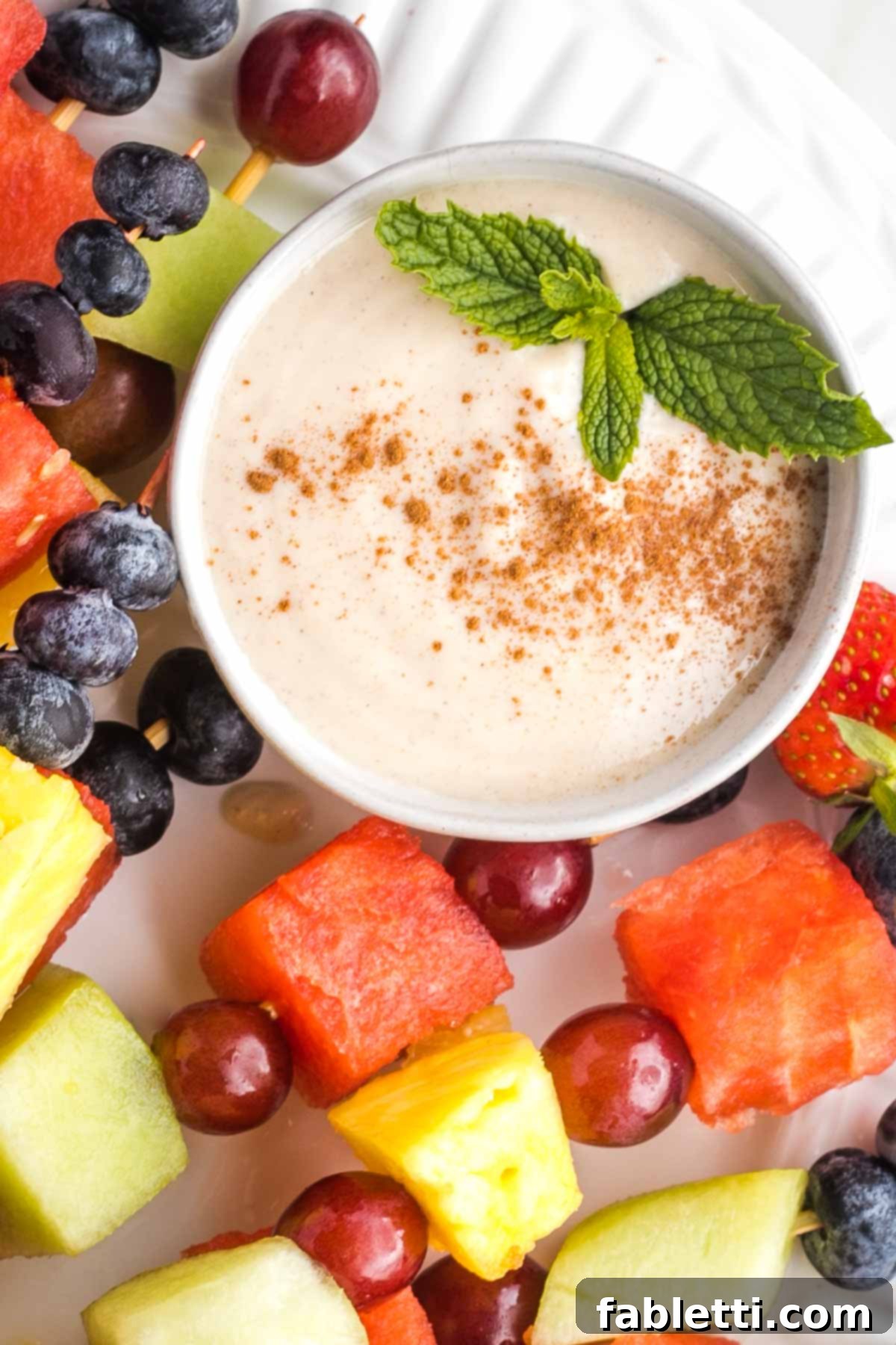 Velvety Vegan Fruit Dip 7 Creamy fruit dip in a bowl, sprinkled with cinnamon and garnished with fresh mint.