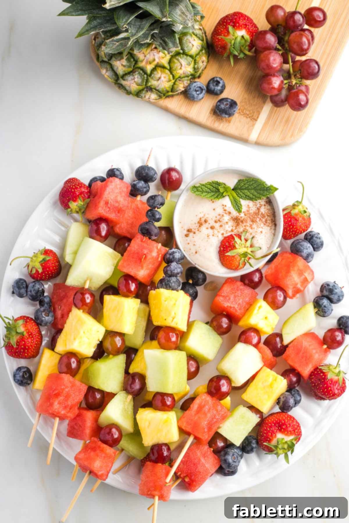 Velvety Vegan Fruit Dip 8 Assorted colorful fruits arranged around a bowl of vegan fruit dip.