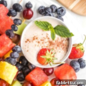 Velvety Vegan Fruit Dip 9 Creamy dip with a sprinkle of cinnamon a strawberry and fresh mint sprig in a small bowl.