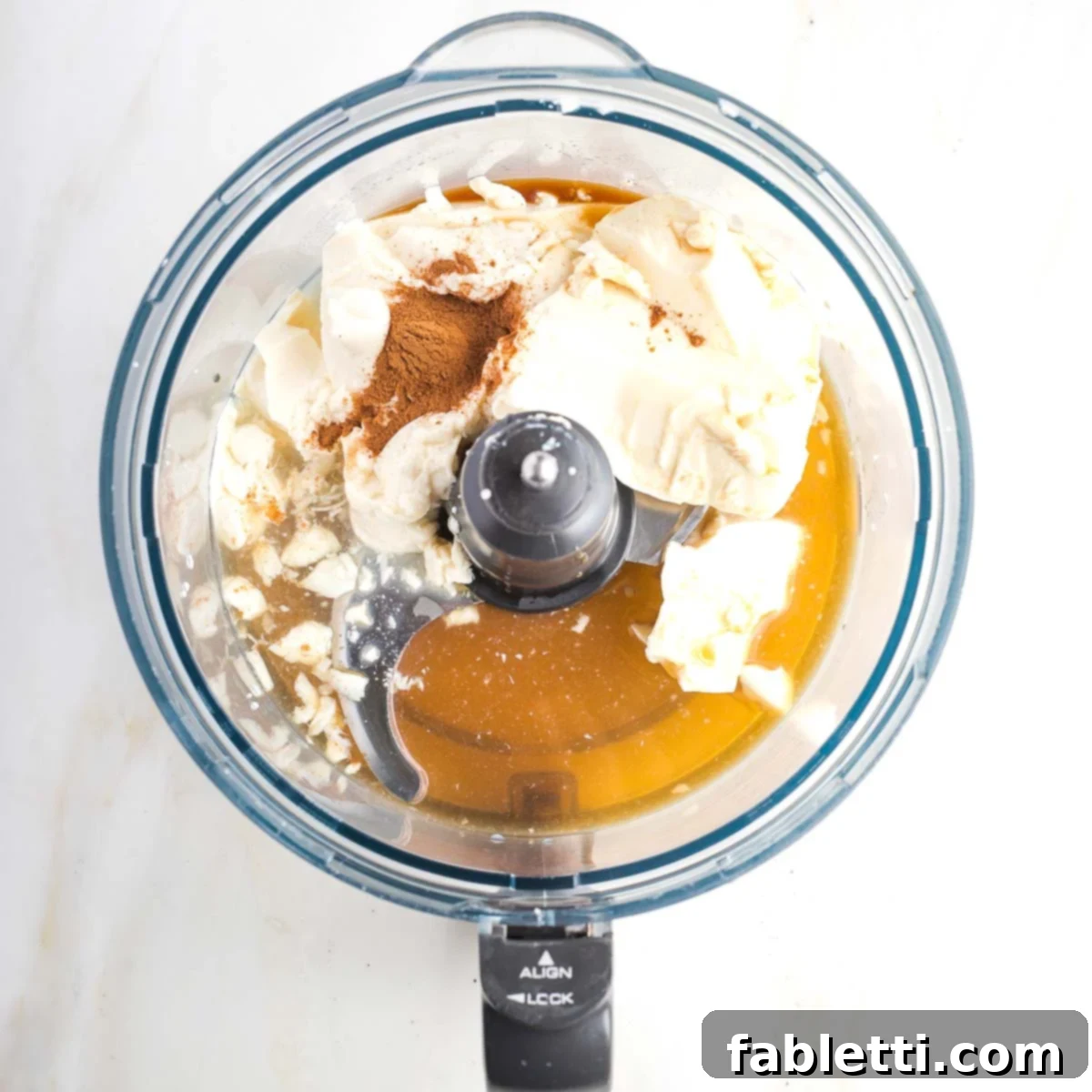 Velvety Vegan Fruit Dip 5 Fruit dip ingredients in the bowl of a food processor, including silken tofu, lemon juice, maple syrup, cinnamon and vanilla.