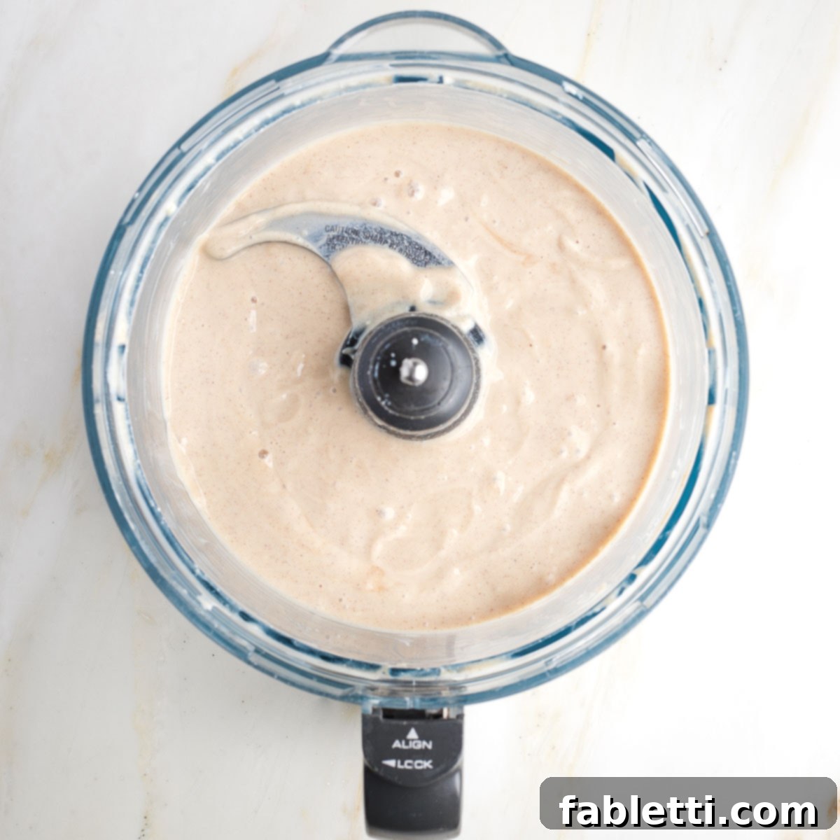 Velvety Vegan Fruit Dip 6 Beige creamy mixture in the bowl of a food processor.